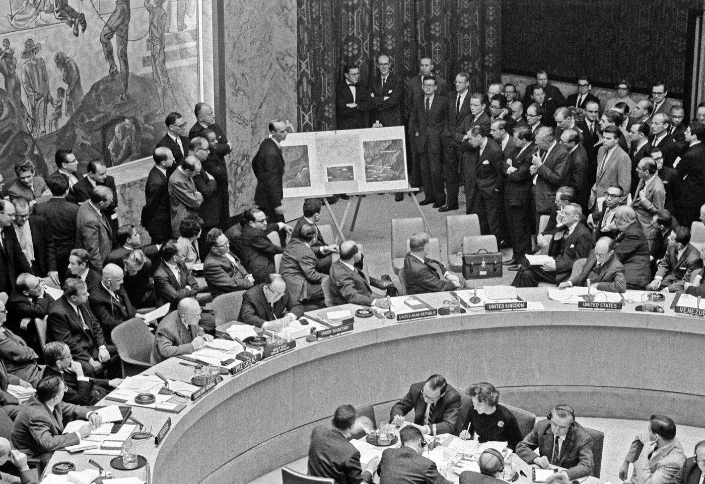 US Ambassador Adlai Stevenson presenting reconnaissance photographs of Soviet missile sites in Cuba to the UN Security Council, 25 October 1962 — the photographs are displayed on easels while delegates crowd around the curved council table