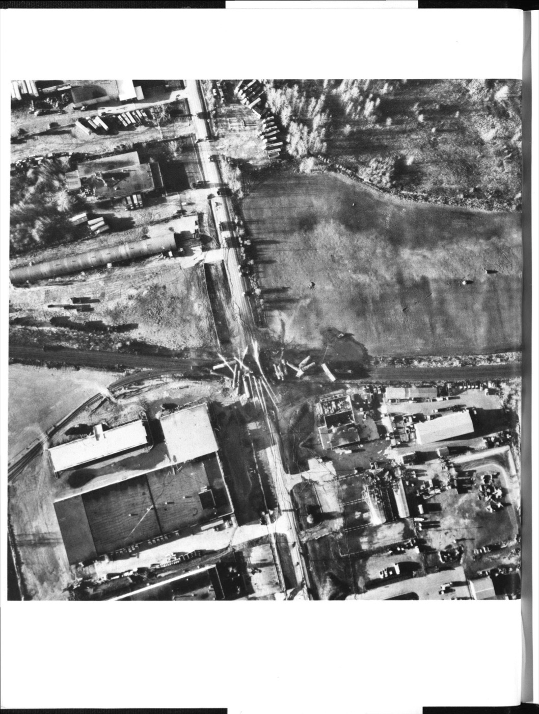 Aerial photograph of the Mississauga derailment site showing scattered rail cars along the track, with industrial property to the south and undeveloped land to the north and northeast